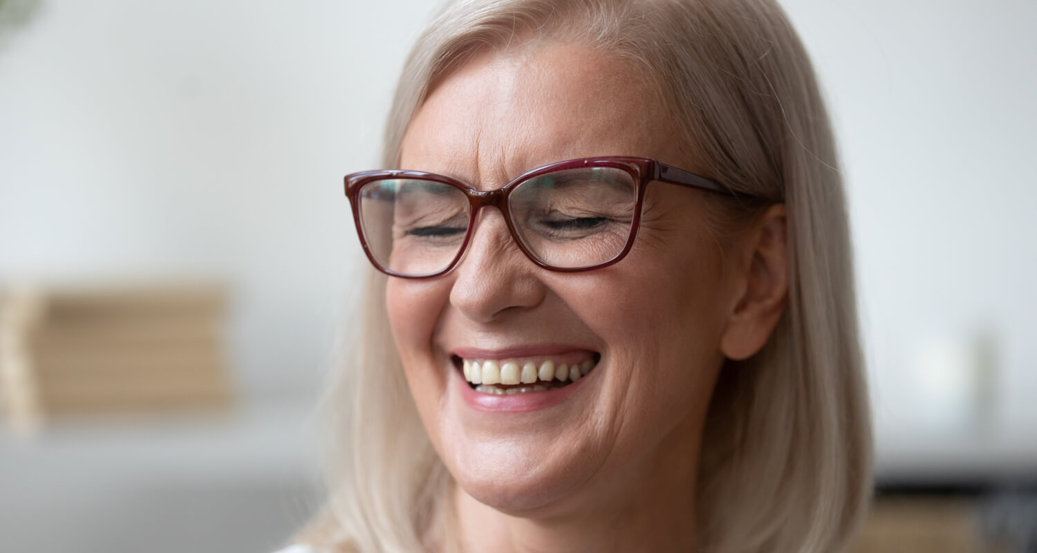 Older woman smiling with glasses.