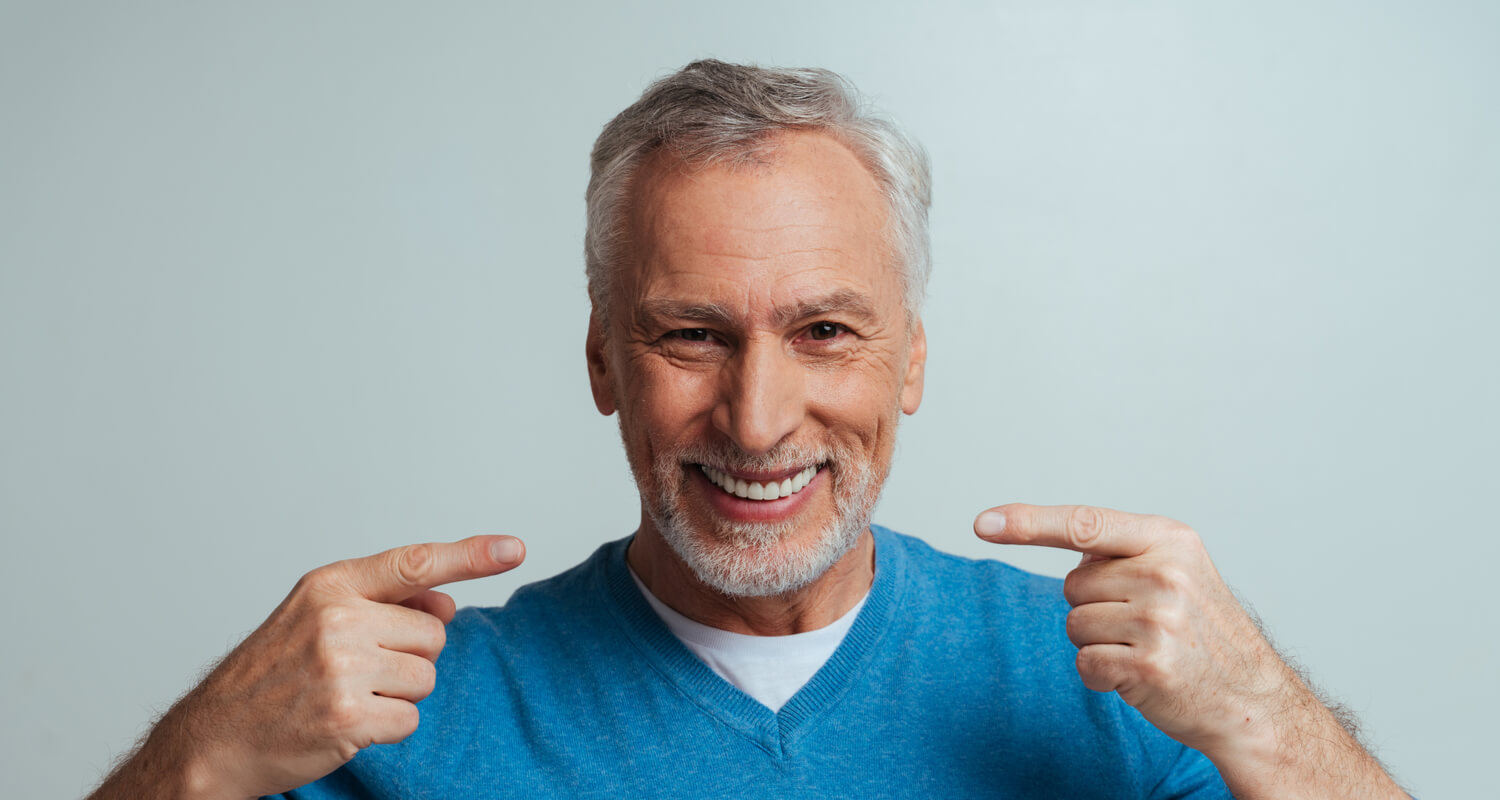 Older man pointing at his wonderful smile.