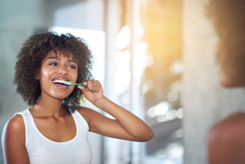 black woman brushing her teeth